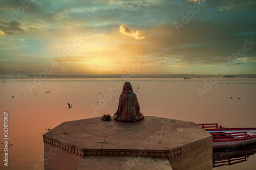 A person is watching beautiful sunrise on the bank of river ganga at ghats of varanasi while meditating photo