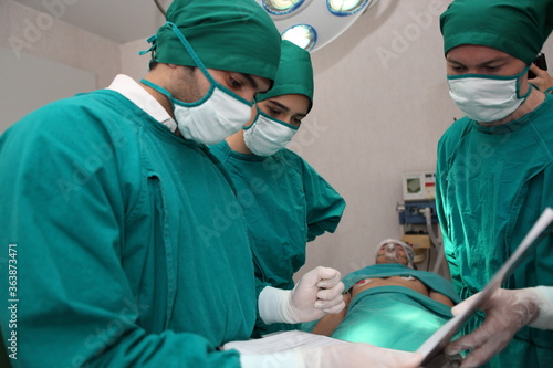  Group of surgeons in hospital operation theater. In the Hospital Operating Room Diverse Team of Professional Surgeons
