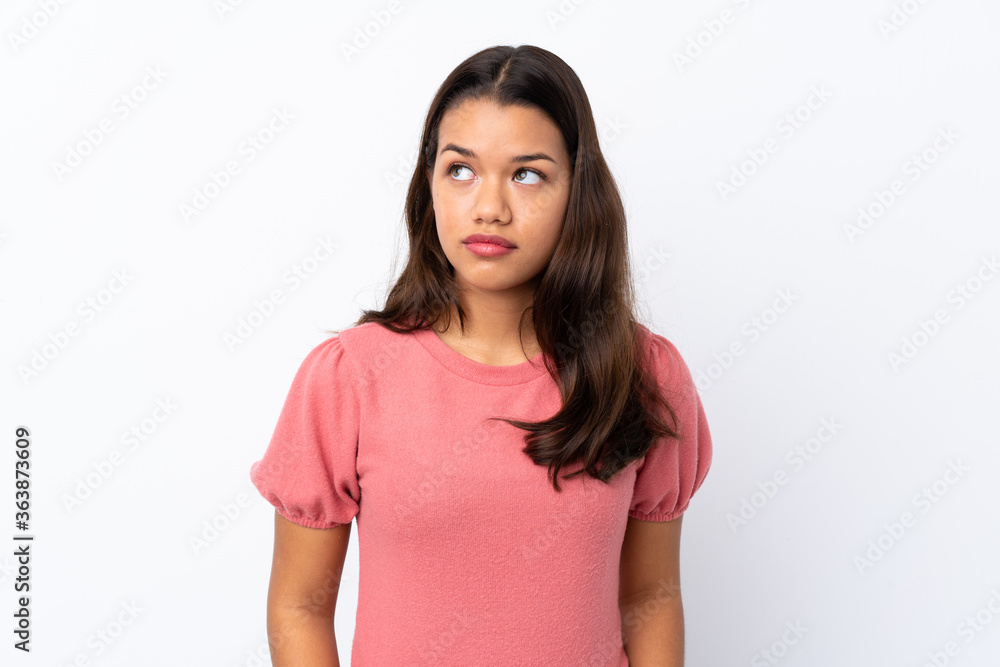 Young Colombian girl over isolated white background making doubts gesture looking side Young Colombian girl over isolated white background making doubts gesture looking side
