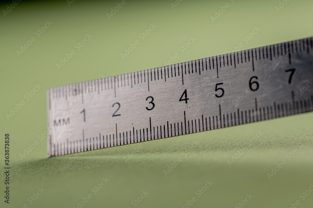 fragment close-up an iron school ruler 20 centimeters long lies on a green table of a schoolboy