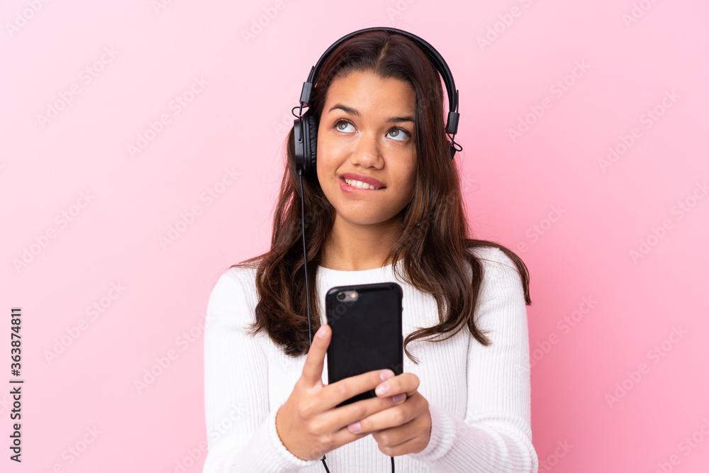 Young woman with earphones over isolated pink wall Young woman with earphones over isolated pink wall