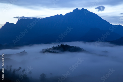 Beautiful landscape scenery with sunlight and fog and Mount Kinabalu as background in Guakon, Sabah, Malaysia © alenthien