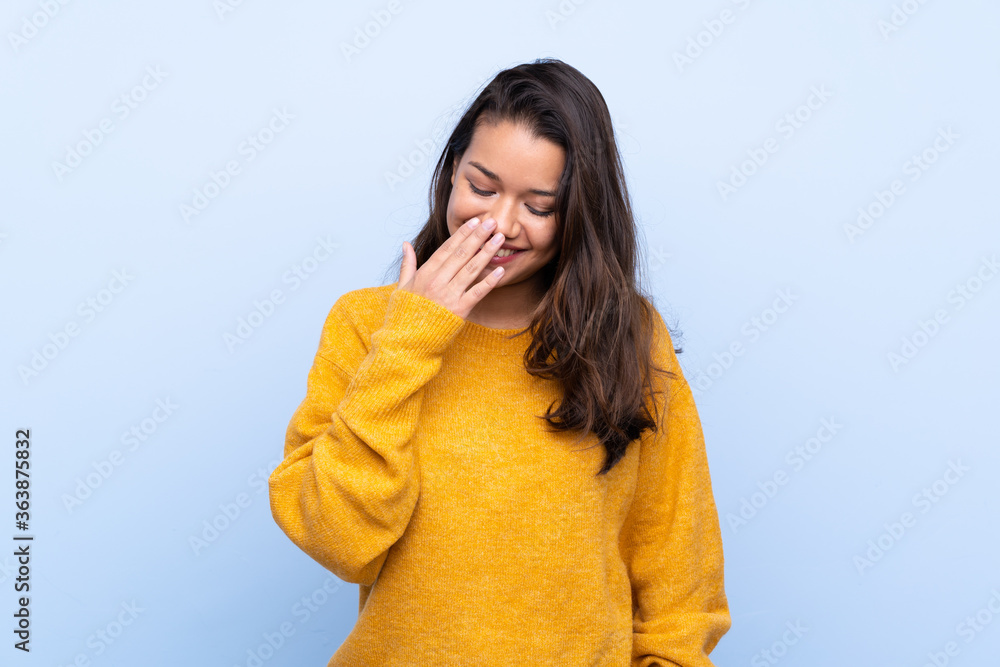 Young Colombian girl with sweater over isolated blue background smiling a lot Young Colombian girl with sweater over isolated blue background smiling a lot