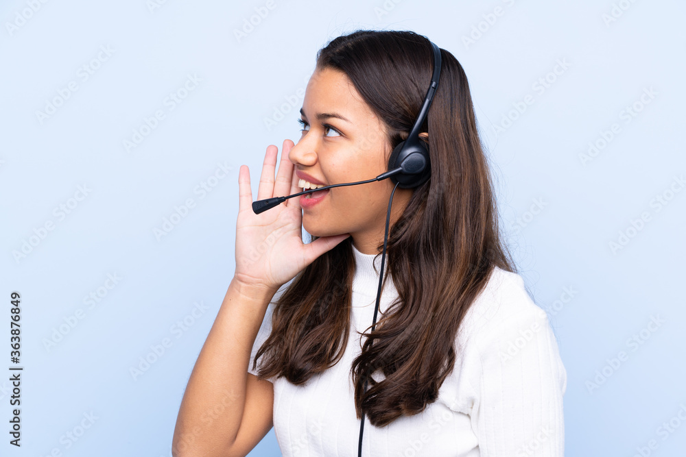 Young telemarketer Colombian woman over isolated blue background shouting with mouth wide open