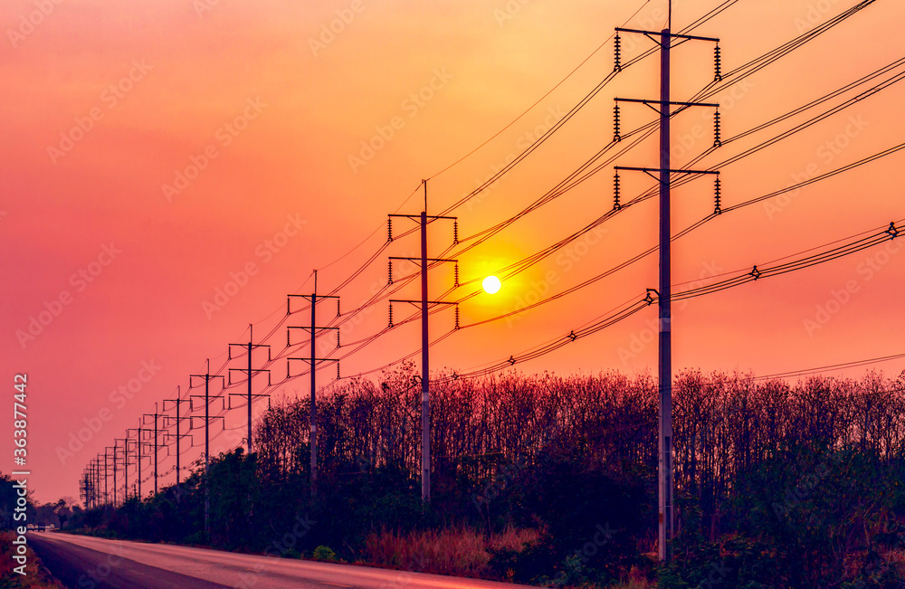 Silhouette of electric pole with cable on dramatic sunset sky along the road