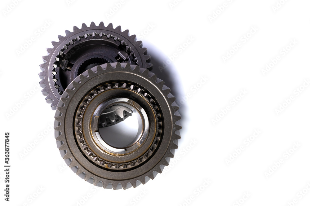 The two new shiny metal gear of the switch box is fronted by a isolated on white background. The concept of new spare parts for car maintenance and repair The two new shiny metal gear of the switch box is fronted by a isolated on white background. The concept of new spare parts for car maintenance and repair