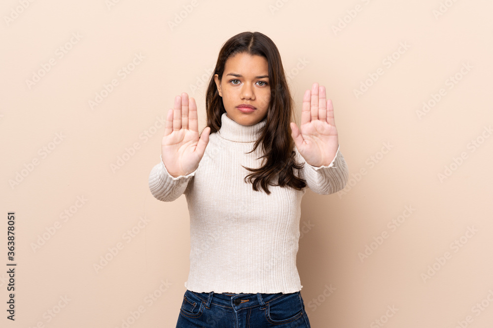 Young Colombian girl over isolated background making stop gesture and disappointed Young Colombian girl over isolated background making stop gesture and disappointed
