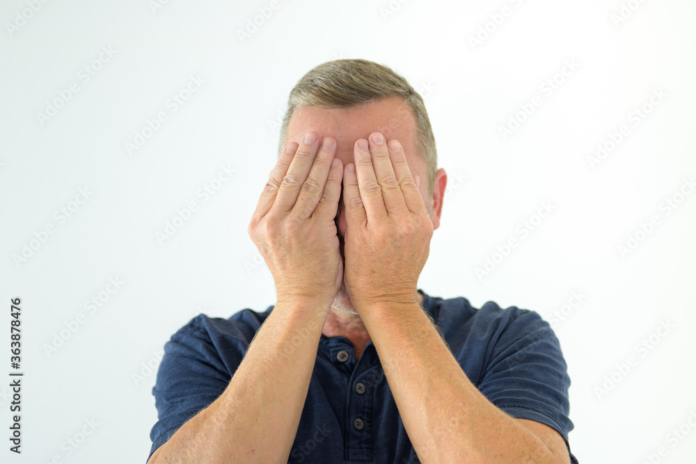 Middle-aged man covering his eyes with his hands Middle-aged man covering his eyes with his hands