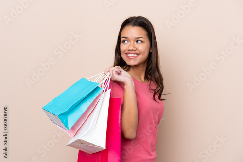 Young Colombian girl with shopping bag over isolated background holding shopping bags and smiling