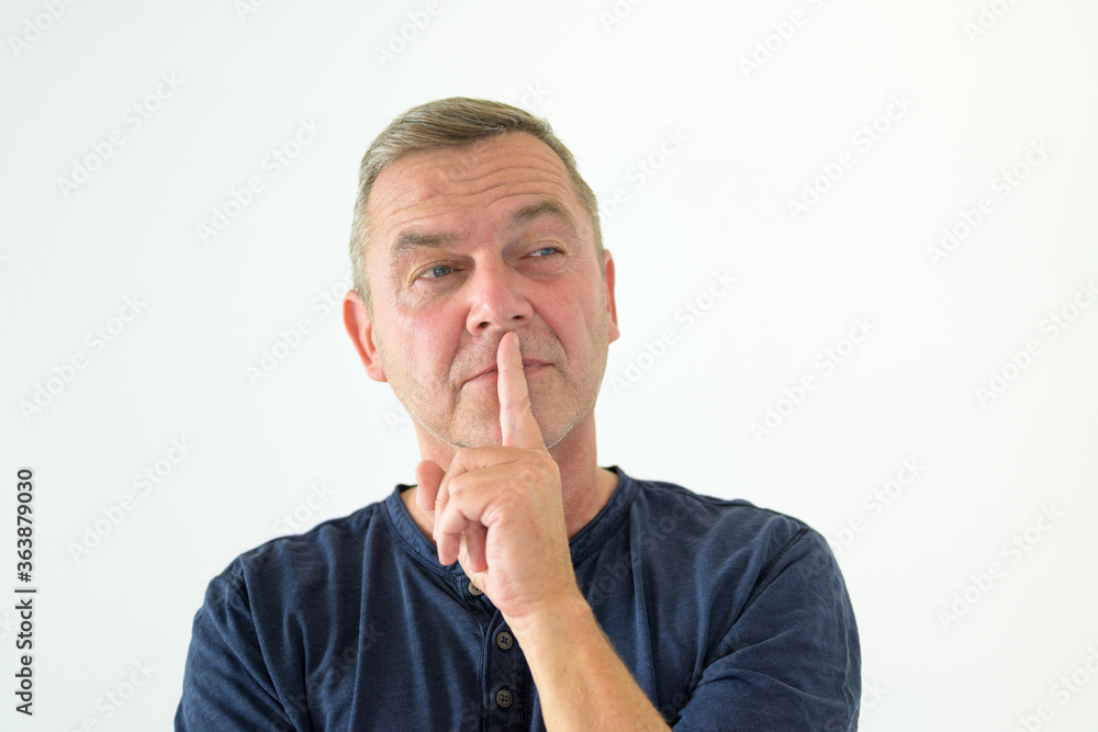 Thoughtful man standing with finger to lips Thoughtful man standing with finger to lips