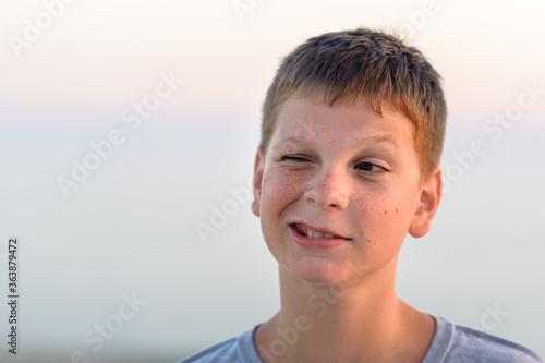 Fototapet Portrait of a grimacing boy, close-up, tan, evening shot.