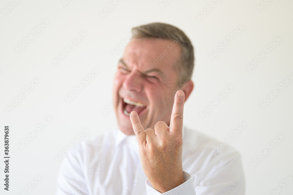 Angry middle-aged man making a Horns gesture