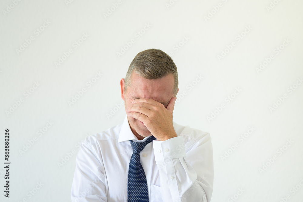 Worried businessman covering his eyes with a hand Worried businessman covering his eyes with a hand