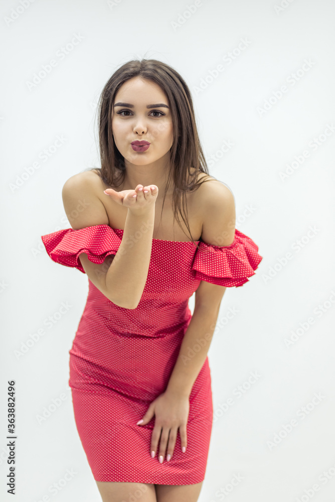 Pretty woman in summer dress sends an air kiss over white background.