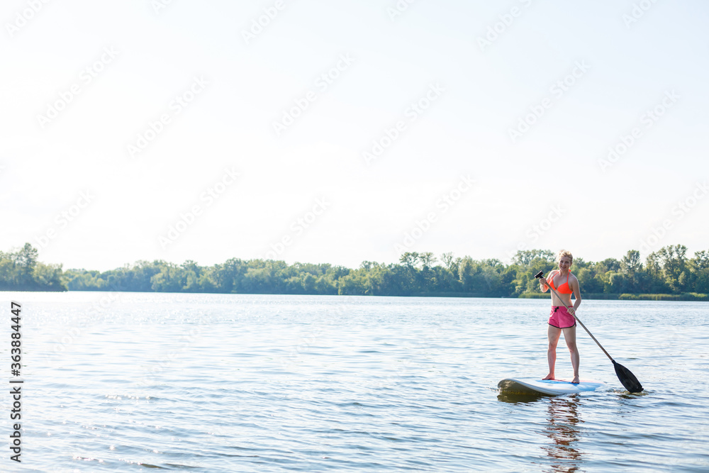 Naklejka premium Action Shot of Young Woman on Paddle Board