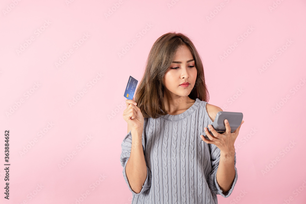 Isolated A woman holds a credit card and looks at the calculator. Isolated A woman holds a credit card and looks at the calculator.