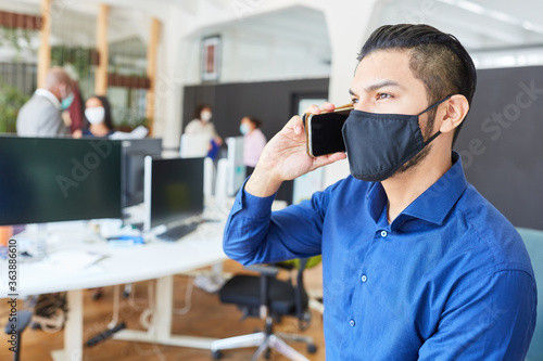 Business man with face mask is talking on smartphone