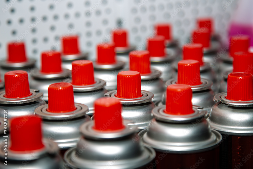 Obraz premium aerosol cans with a bright red lid are in a row. Macro photo. Selective focus on the nozzle. paint