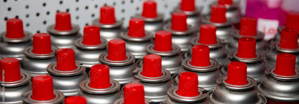 aerosol cans with a bright red lid are in a row. Macro photo. Selective focus on the nozzle. paint aerosol cans with a bright red lid are in a row. Macro photo. Selective focus on the nozzle. paint