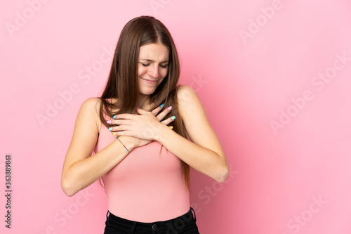 Young caucasian woman isolated on pink background having a pain in the heart