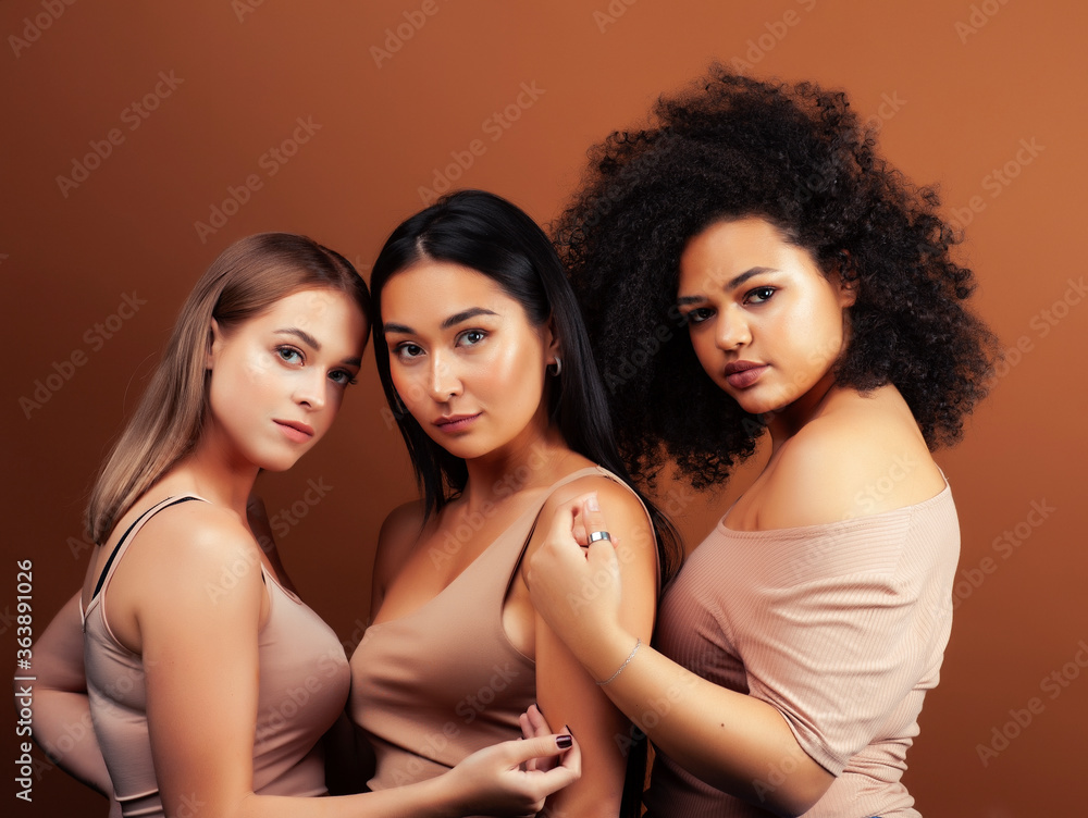 young pretty asian, caucasian, afro woman posing cheerful together on brown background, lifestyle diverse nationality people concept young pretty asian, caucasian, afro woman posing cheerful together on brown background, lifestyle diverse nationality people concept