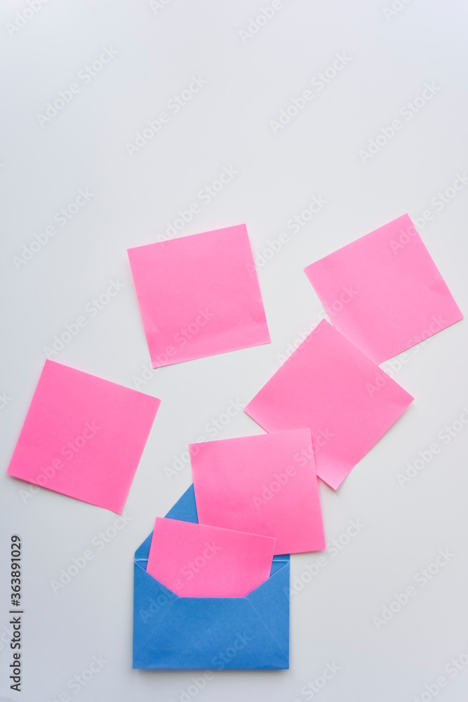 selective focus, pink paper stickers in chaos and blue envelope on the white background selective focus, pink paper stickers in chaos and blue envelope on the white background
