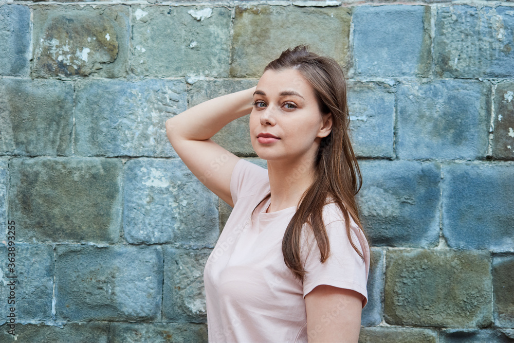 Portrait of a young woman in a pink T-shirt against the wall Portrait of a young woman in a pink T-shirt against the wall