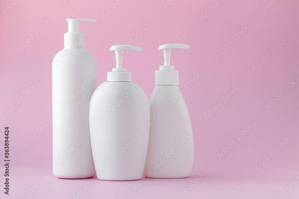 White plastic bottles on a pink background, a set of cosmetic containers with a dispenser. Copy space, empty place for text. Toiletries, pump lotion. Moisturizing cream for body and face. White plastic bottles on a pink background, a set of cosmetic containers with a dispenser. Copy space, empty place for text. Toiletries, pump lotion. Moisturizing cream for body and face.