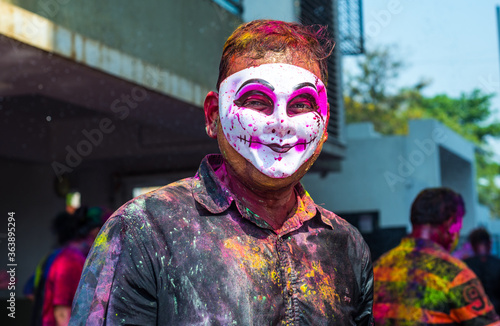 Close up of a man wearing mask on the occasion of Holi - a festival of colors. Funny face mask smothered with colors.
