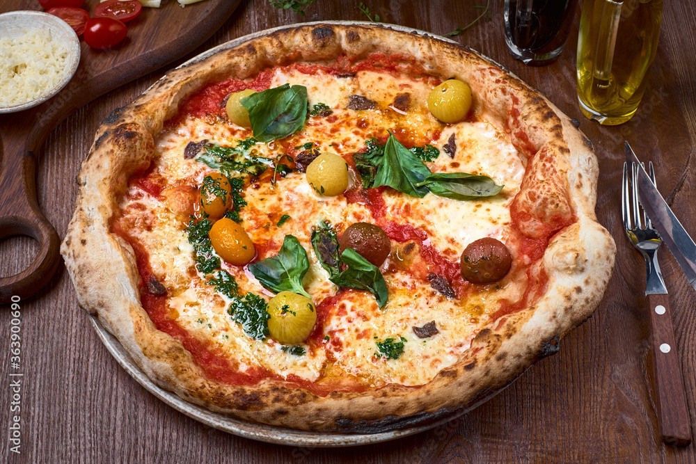 Pizza Napoli, Classic italian pizza with tomato sauce, mozzarella cheese, anchovy and basil on dark a wooden table. Pizza Napoli, Classic italian pizza with tomato sauce, mozzarella cheese, anchovy and basil on dark a wooden table.