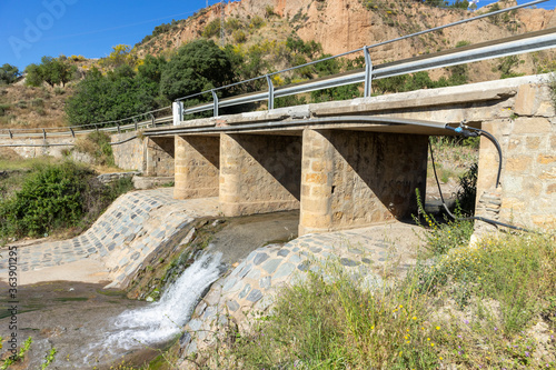 water passing over a bridge with vegetation