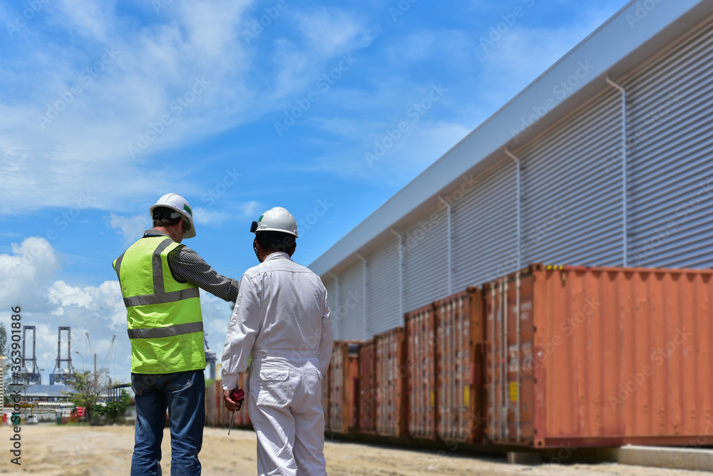 Workers having discussion against cargo containers in harbor