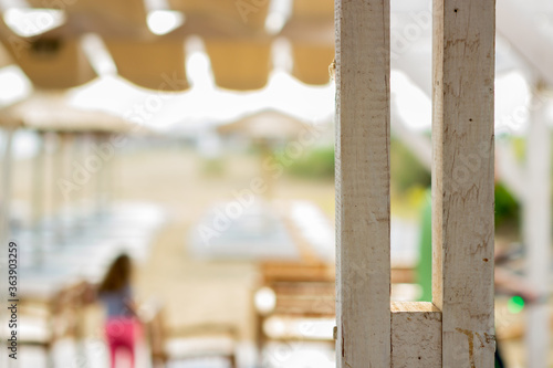 Focus on the white wooden beam on the beach bar. It is a beautiful summer time and it is very sunny. Copy space.