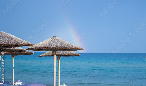 Fototapeta Naklejka Na Ścianę i Meble -  Reed umbrellas on the beach and behind it is a beautiful blue sea and blue sky. Copy space.