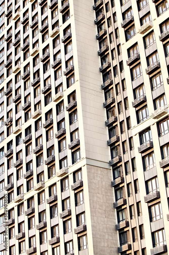 Fototapeta premium Modern residential skyscrapers facade close-up. Commercial real estate. Modern apartment buildings design. Many windows in the wall of a modern house. Residential city tower.