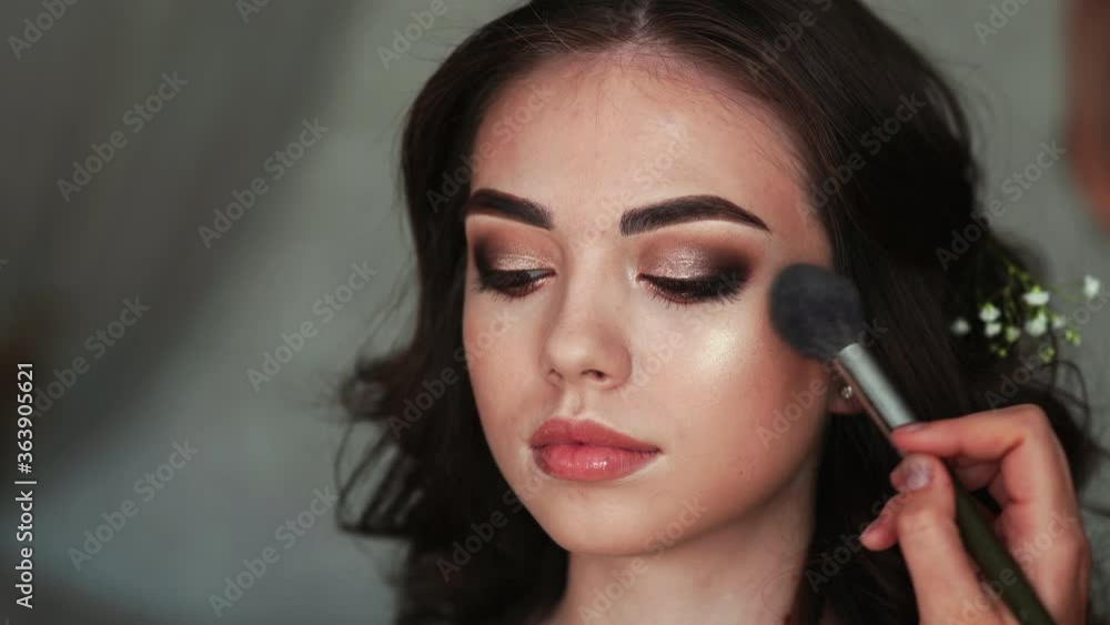 Girl make-up artist applies powder on the face of the model. Girl make-up artist applies powder on the face of the model.