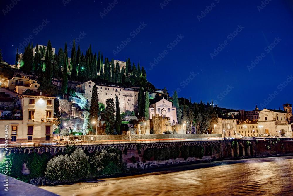 Night photo along the Adige river overlooking the Roman theater and San Pietro castle, city of Verona, Italy.