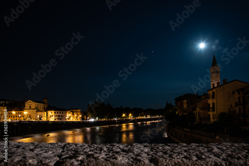 Night photo with moon and star Venus along Adige river with view of the church of Santa Anastasia, city of Verona, Italy.