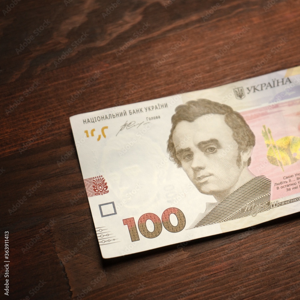 New Ukrainian banknotes. Paper 100 or one hundred hryvnia notes with famous Ukrainian historical figure Taras Shevchenko on it. High angle view. Close up shot. - obrazy, fototapety, plakaty 