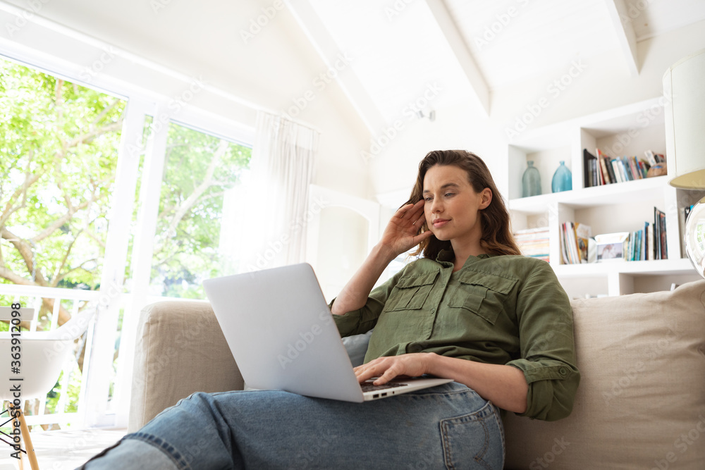 Woman using laptop while sitting on couch at home Woman using laptop while sitting on couch at home