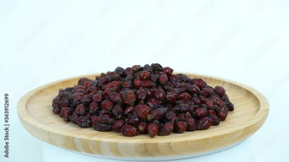 Rose hips on the tray rotating, close up view.  Dog rose rotating on the tray in white background. Professional studio light.