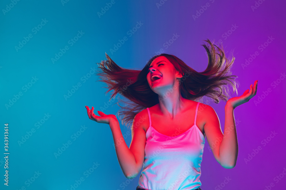 Dancing, hair blowing, inspired. Caucasian young woman's portrait on gradient background in neon light. Beautiful female model. Concept of human emotions, facial expression, sales, ad. Copyspace. Dancing, hair blowing, inspired. Caucasian young woman's portrait on gradient background in neon light. Beautiful female model. Concept of human emotions, facial expression, sales, ad. Copyspace.