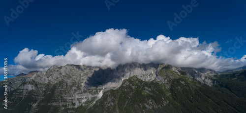 High alps in the clouds on a blue background