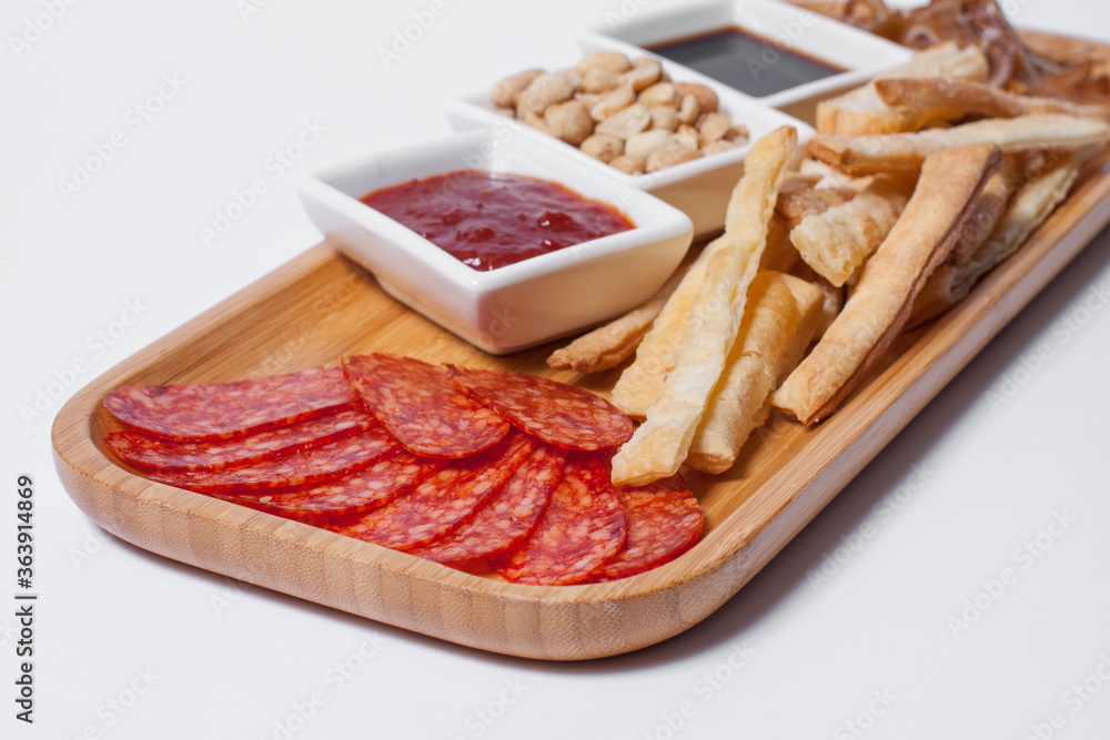 beer appetizers set with peanuts, salami, toasts, and cheese on wooden board isolated beer appetizers set with peanuts, salami, toasts, and cheese on wooden board isolated