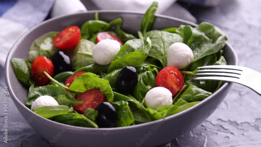 Vegetarian and, organic food concept. Caprese Italian or Mediterranean salad. Tomato mozzarella basil leaves black olives and olive oil rotate Vegetarian and, organic food concept. Caprese Italian or Mediterranean salad. Tomato mozzarella basil leaves black olives and olive oil rotate
