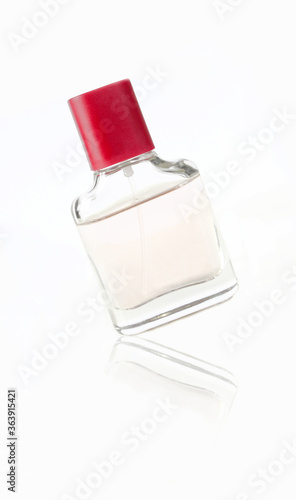 Small parfume bottle with red cap on, isolated on white background.
