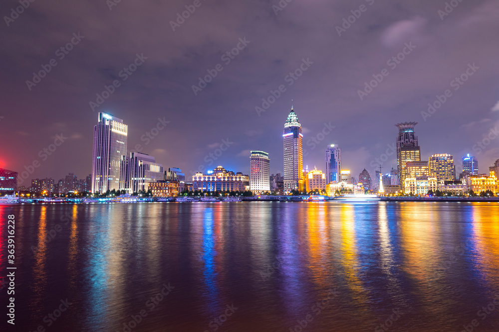 There are many tall buildings by the river in the evening.