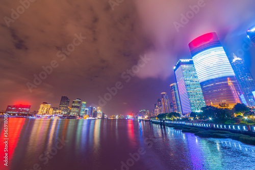 There are many tall buildings by the river in the evening.