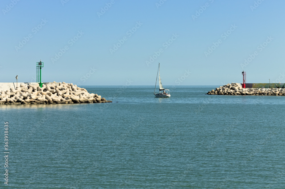 The entrance of Pesaro harbour with tetrapod breakwaters, and a green and a red lighthouse on the piers (Marche, Italy, Europe)