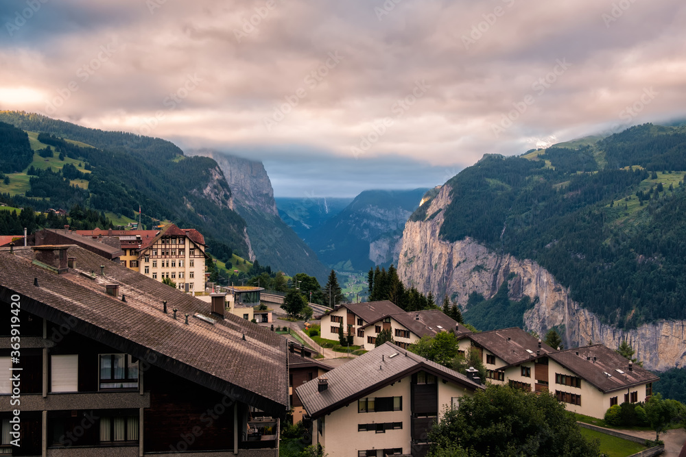 View on swiss alpine village Wengen and the cliffs of the Lauterbrunnen valley under cloudy skies in morning in summer
